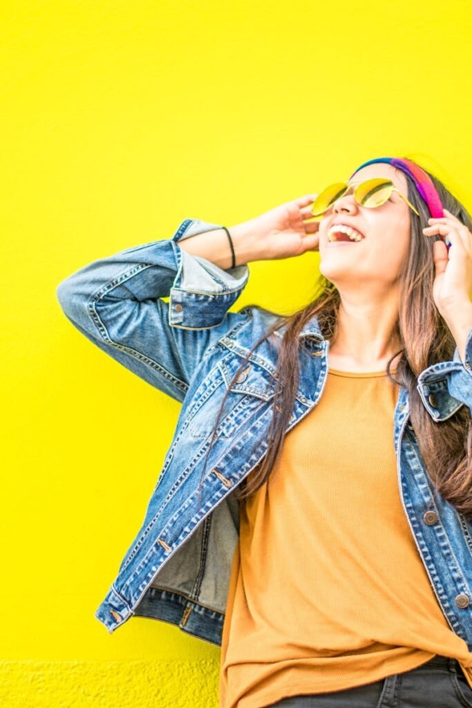 Smiling Woman Looking Upright Standing Against Yellow Wall