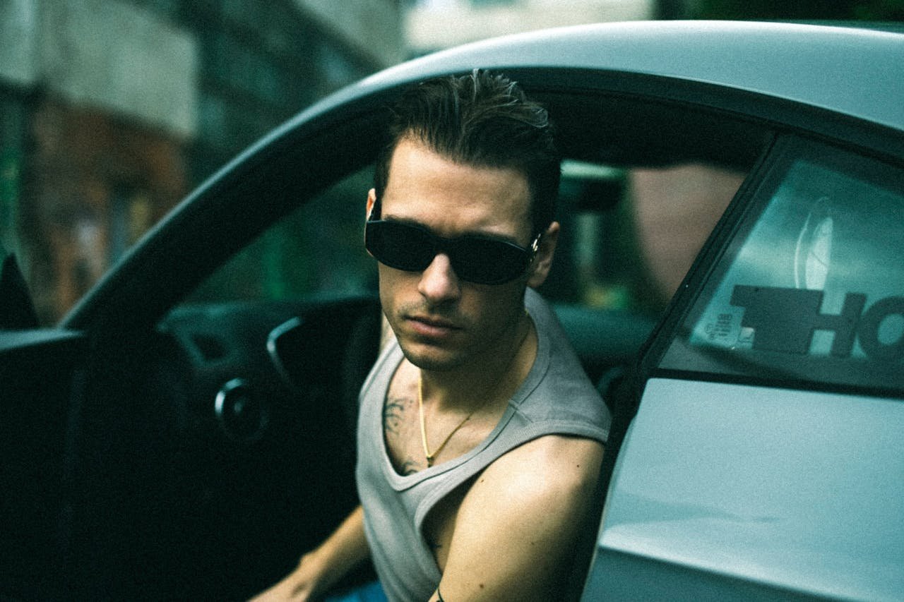 Young Man in a Tank Top and Sunglasses Sitting in a Car